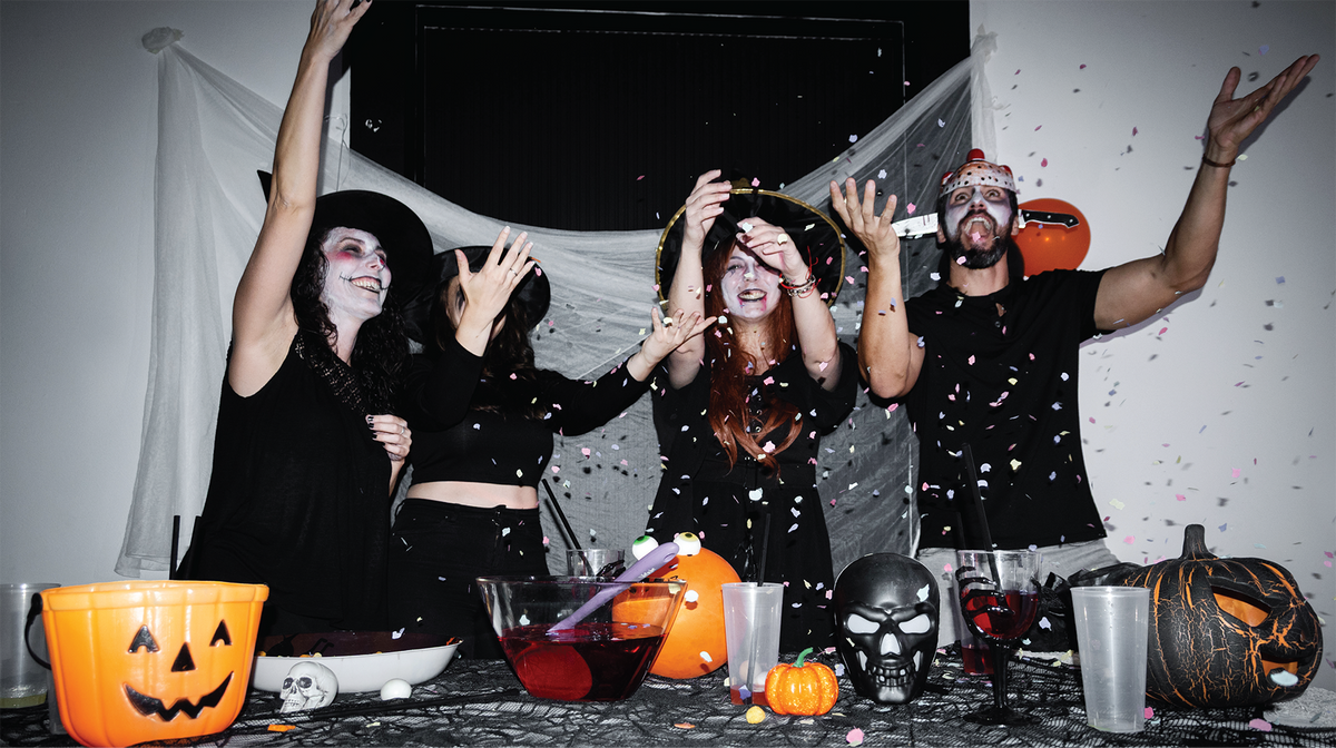 People dressed in Halloween costumes laughing and mingling at a Halloween celebration.