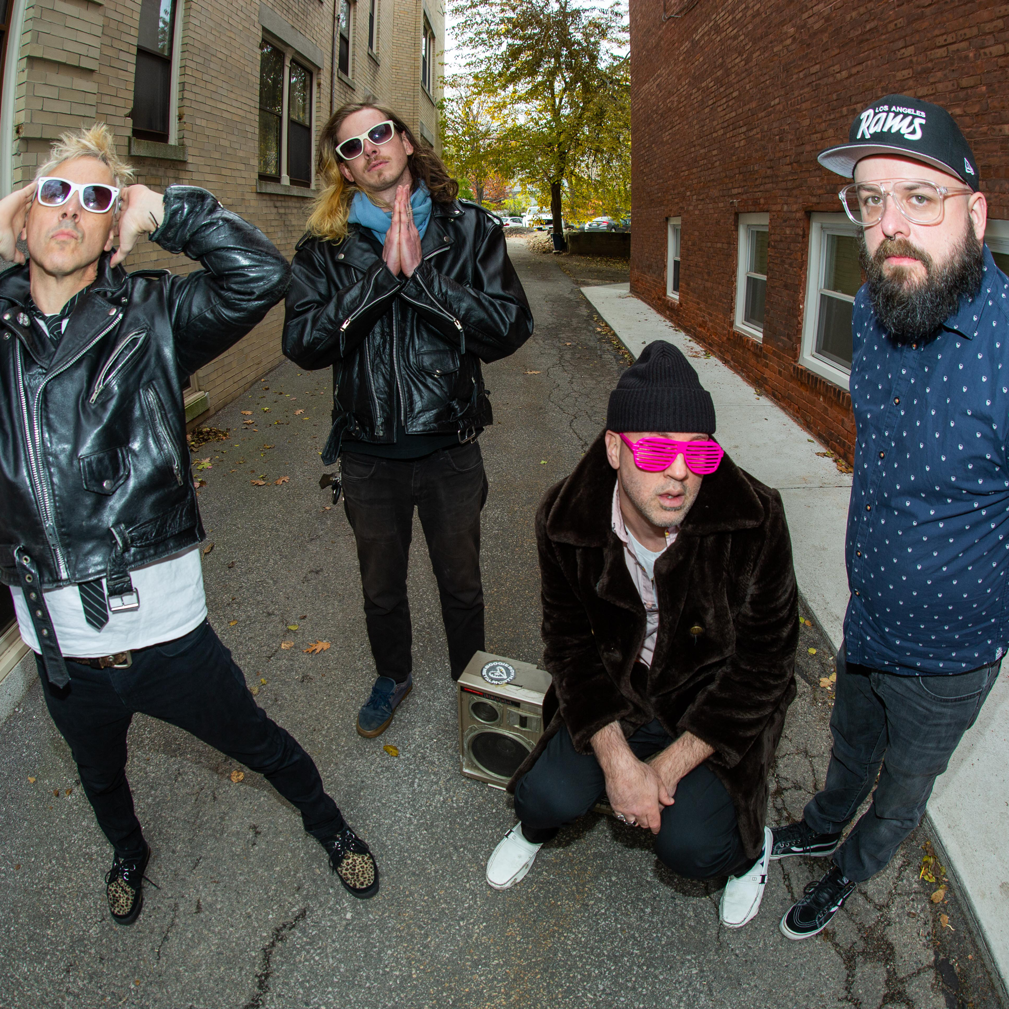 Image of Baabes - a ONE on Stage band. Four people in alleyway. One person sits on a music player.