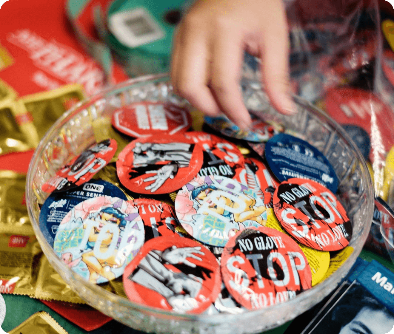 Hand reaching into a bowl filled with colorful stickers, including 'No Glue' and 'Stop' designs.