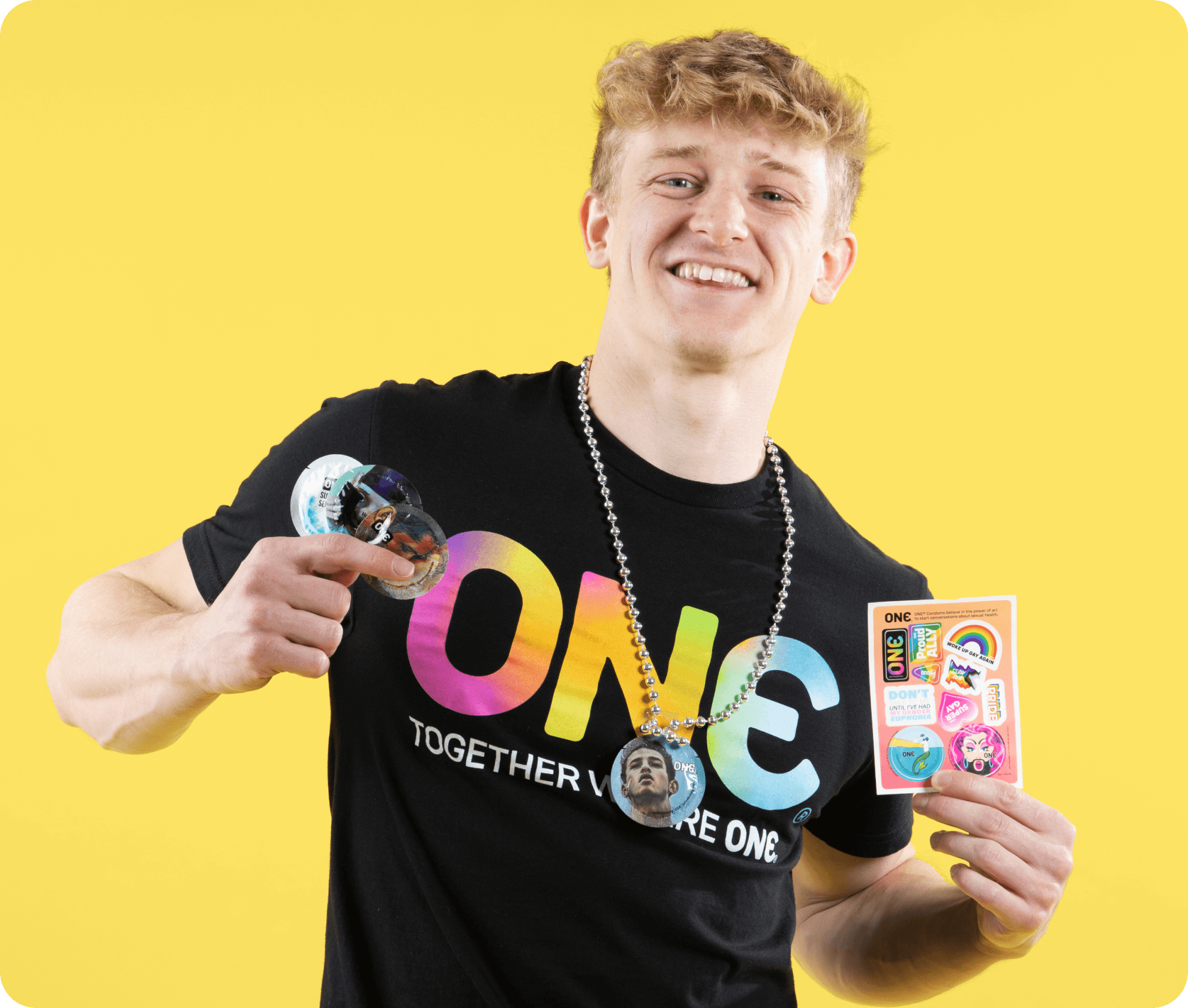 Person wearing a black t-shirt with colorful text and holding a card against a yellow background