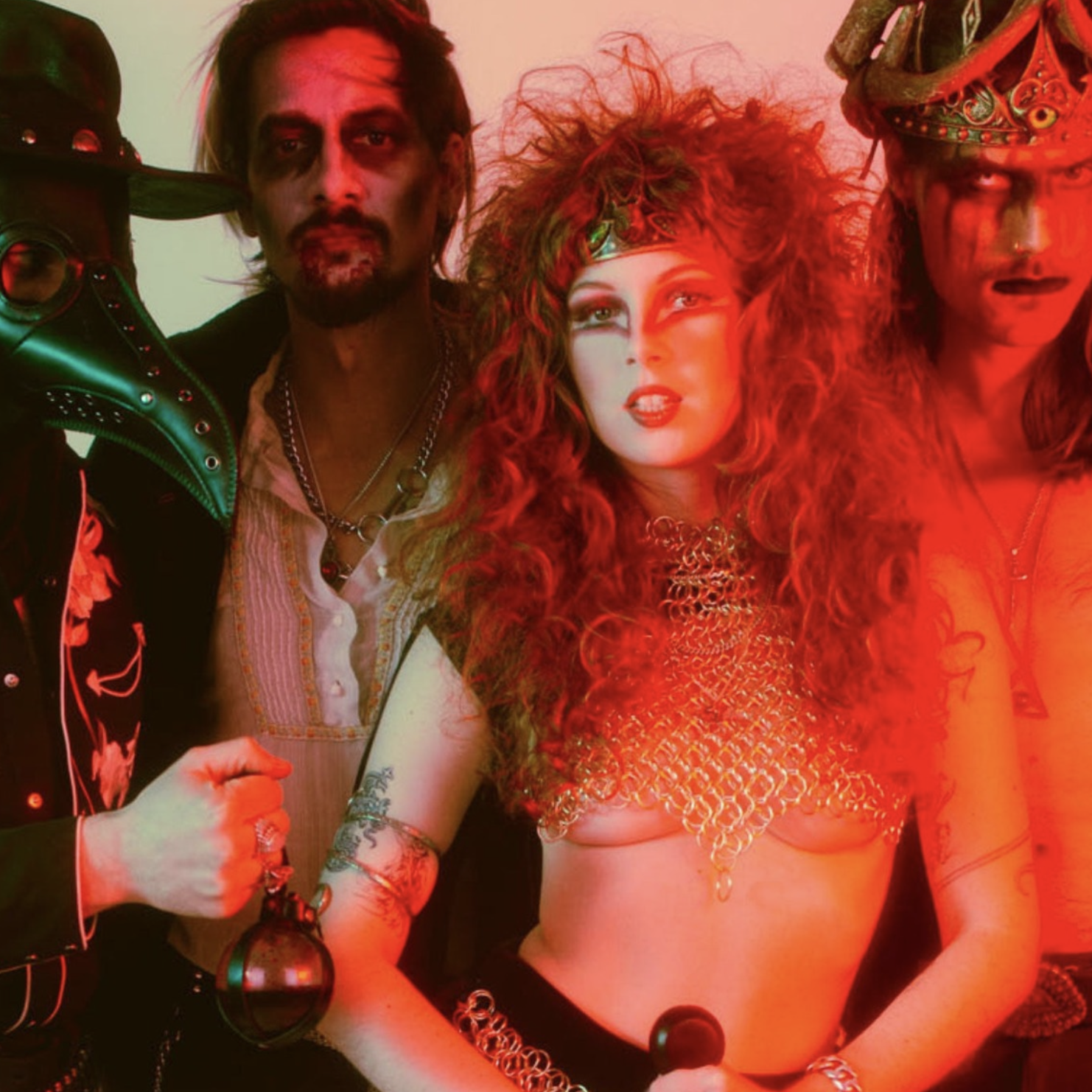 Three people in elaborate costumes with a red and orange filter