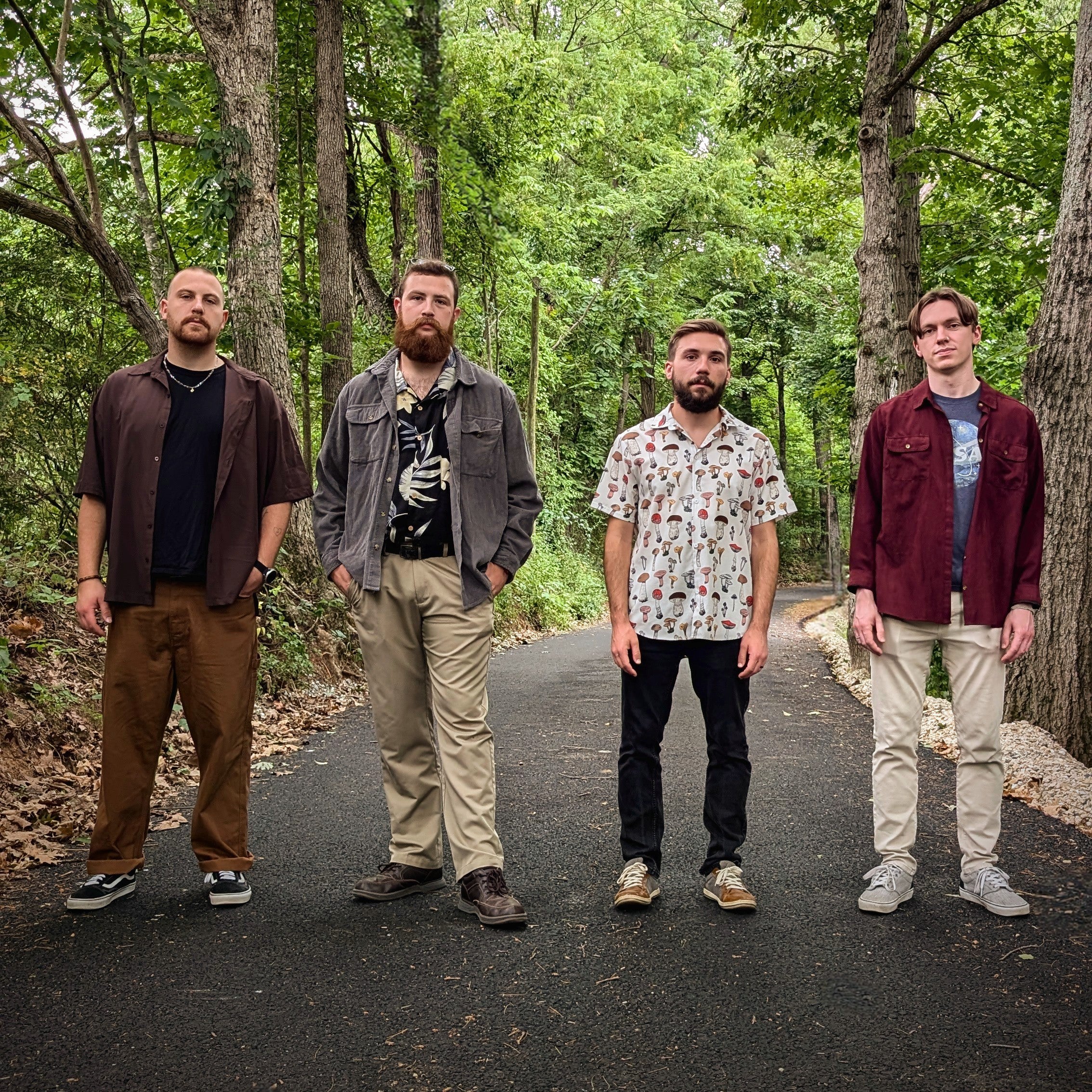 Image of Almost Honest - a ONE on Stage band. Four band members standing on path in woods. 
