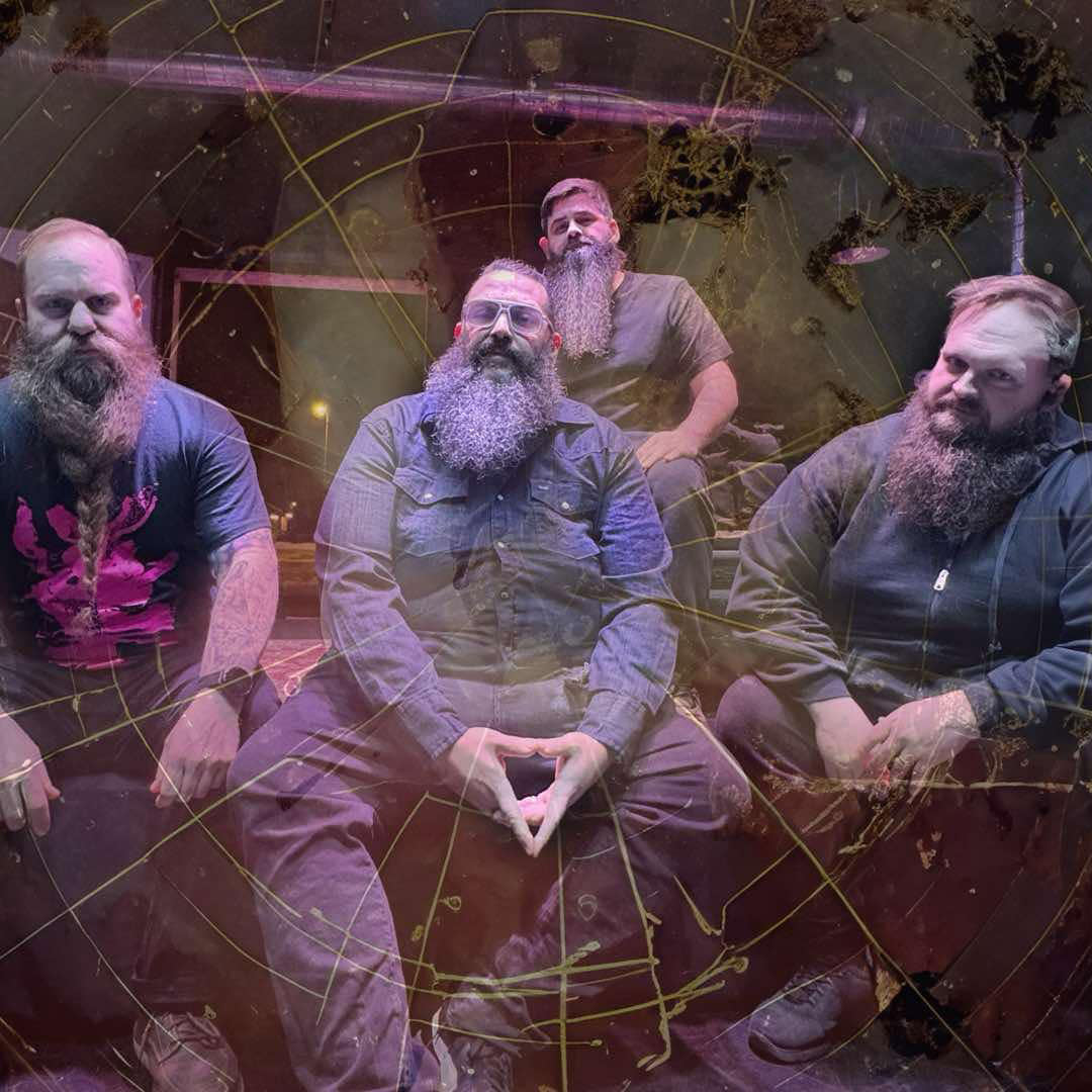 Four men with beards sitting together in a casual setting.