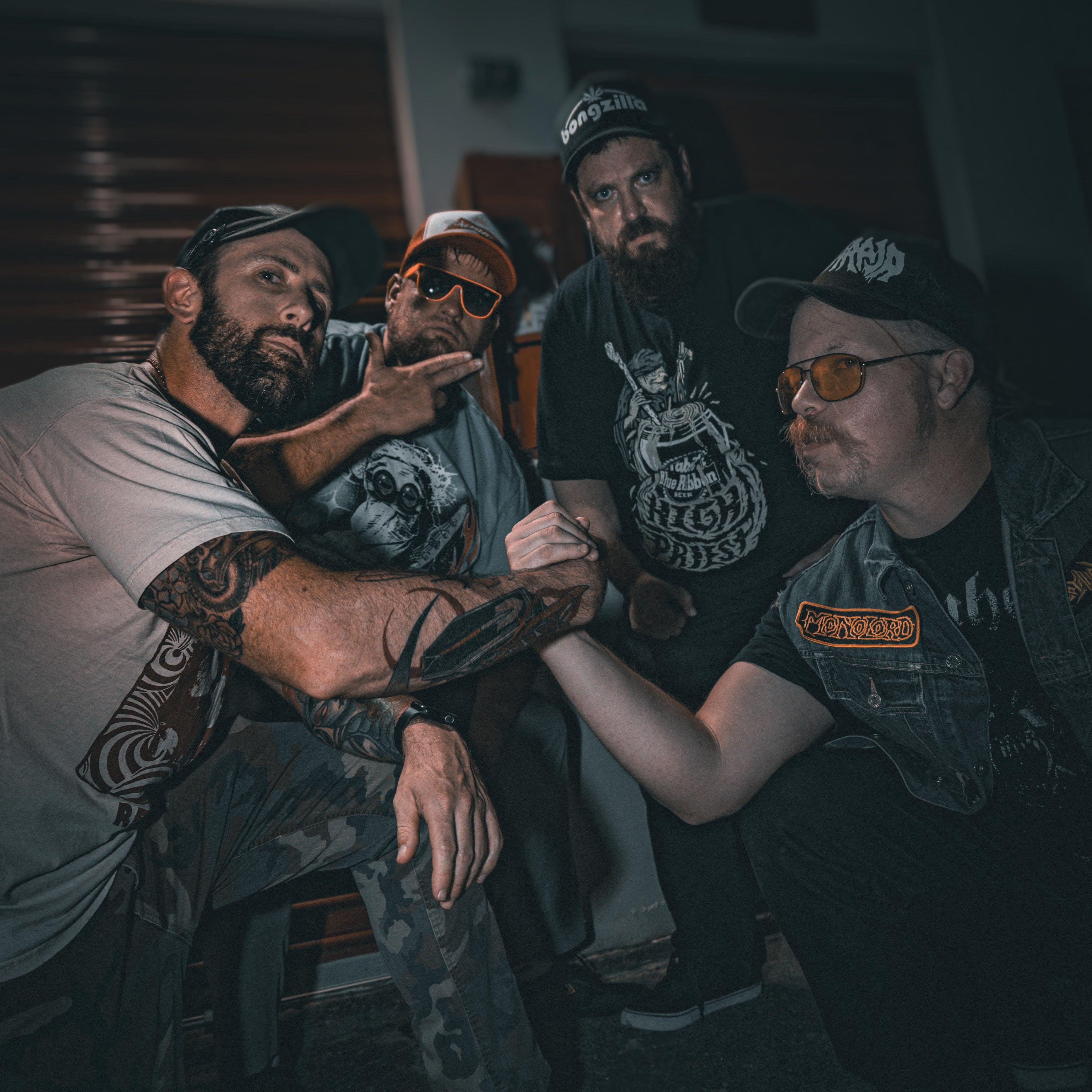 Image of Weed Demon - a ONE on Stage band. Image shows four band members, two shaking hands, two looking at camera. 