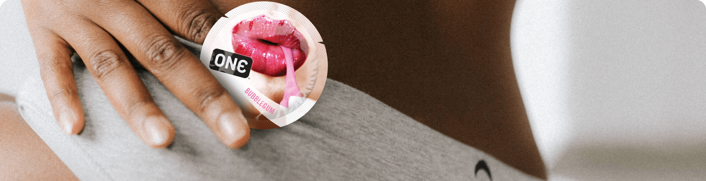 Hand holding a pink and white product labeled 'ONE' against a blurred background